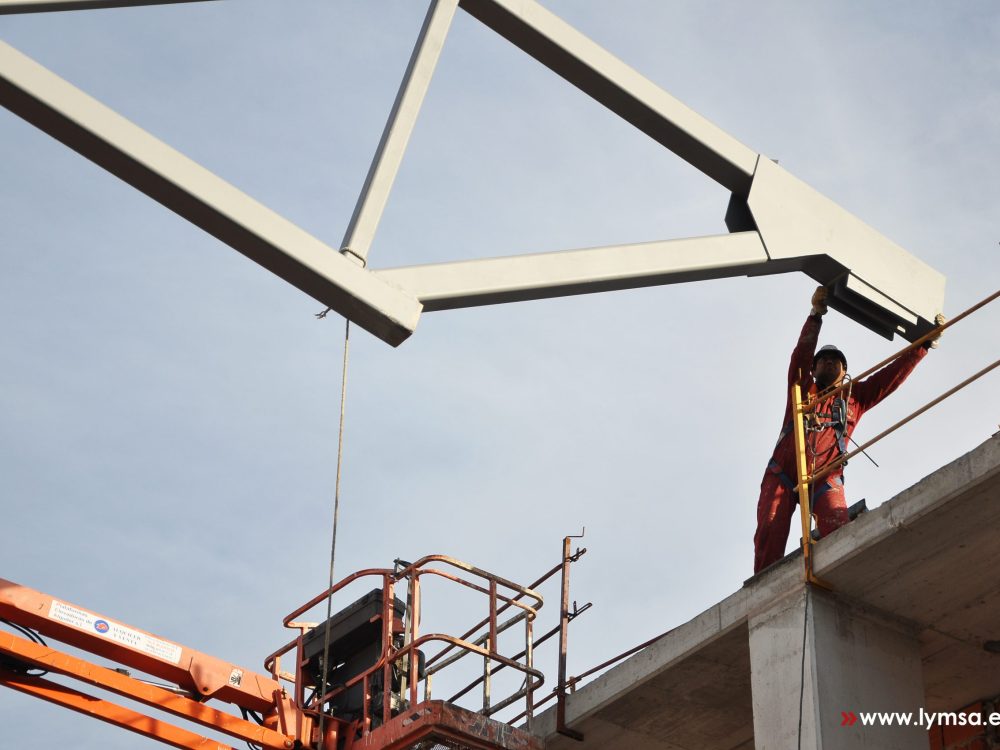 Operario colocando una estructura metálica en su lugar para unirla con las demás